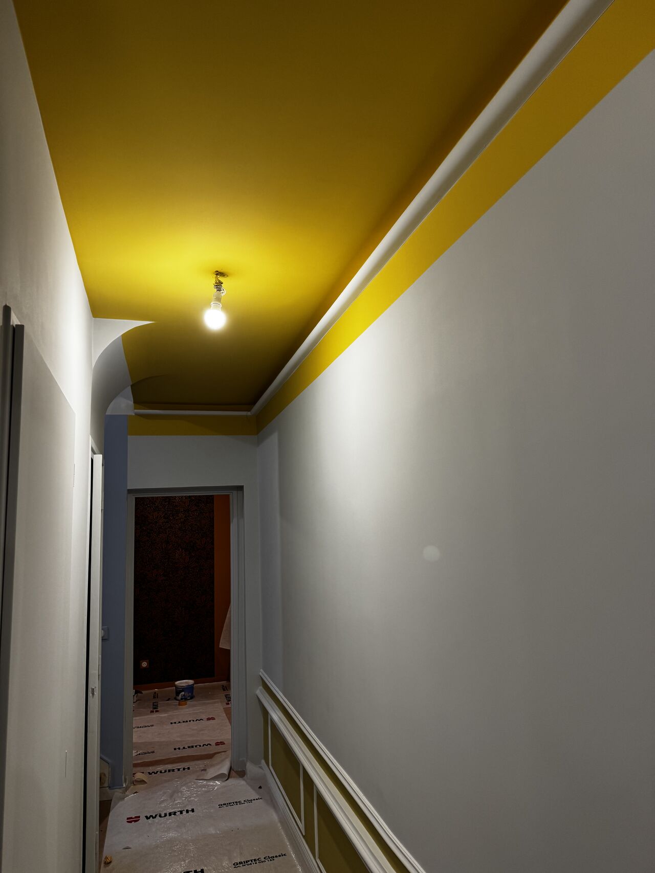 Couloir avec plafond jaune et moulures blanches